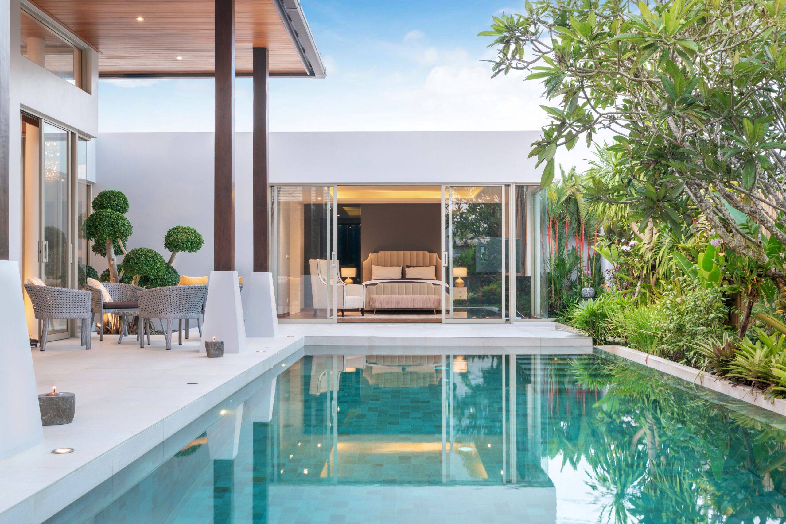 Moderner GFK Pool an Villa mit Glasfront und tropischer Gartenumgebung