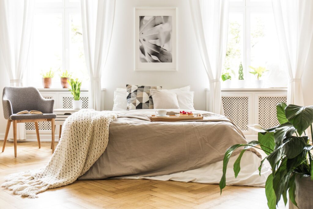 Helles Schlafzimmer mit weißer Alpaka Bettdecke und frischen Blumen, Symbol für natürlichen Schlafkomfort und nachhaltige Materialien.