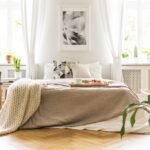 Helles Schlafzimmer mit weißer Alpaka Bettdecke und frischen Blumen, Symbol für natürlichen Schlafkomfort und nachhaltige Materialien.